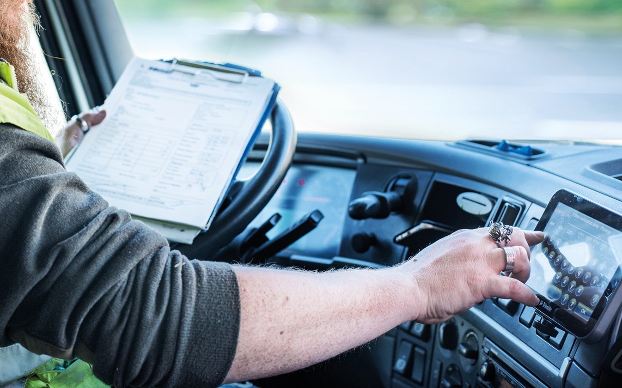 Conducteur au volant de son camion qui manipule l'informatique embarquée