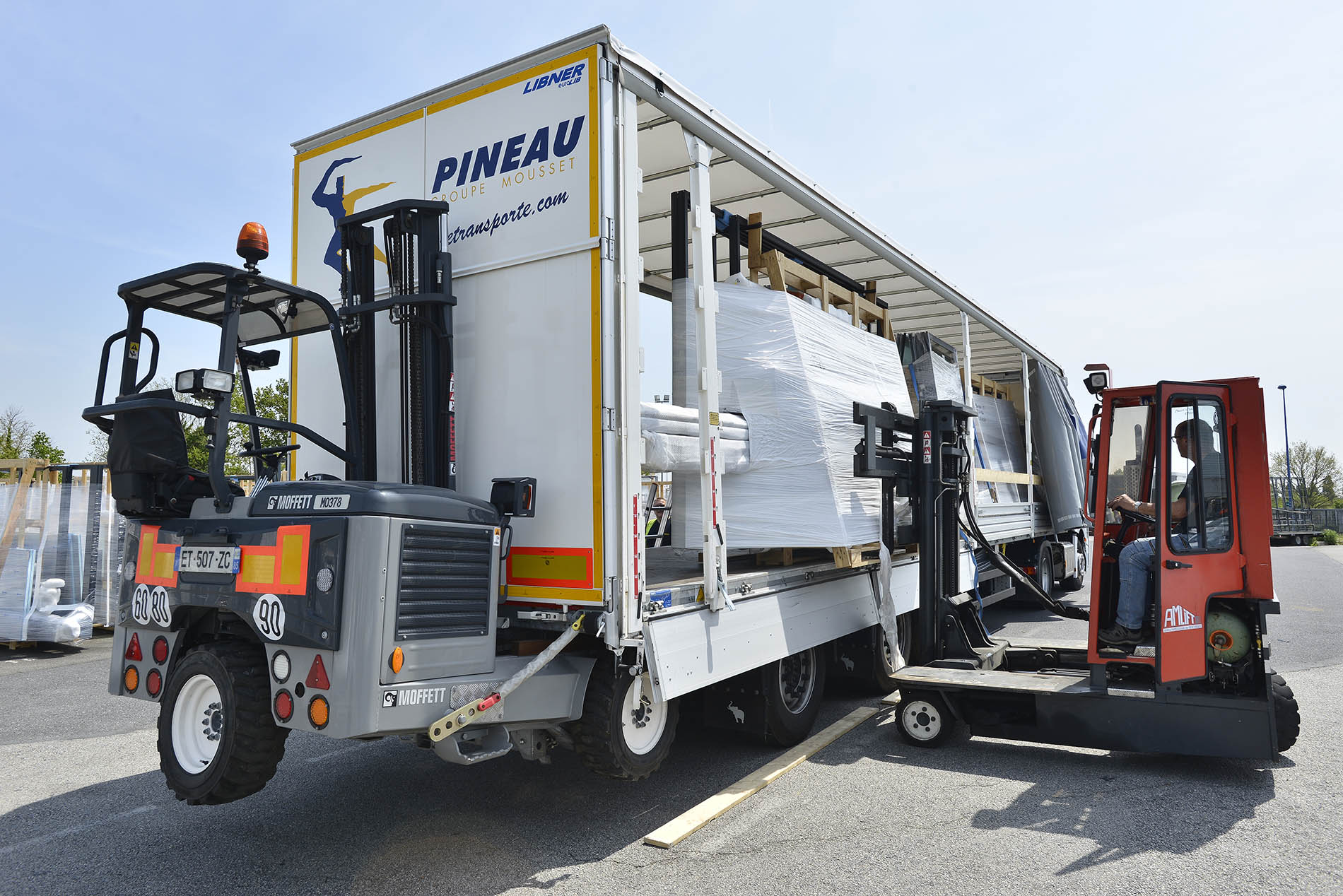 Conducteur PINEAU qui décharge de la menuiserie de son camion avec un chariot embarqué