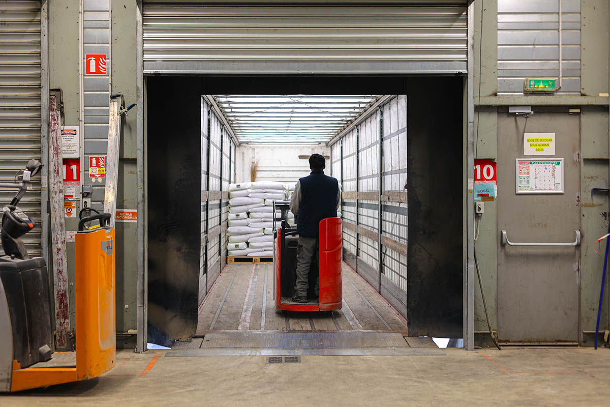 Agent de quai qui charge un camion avec des palettes de farines meunières