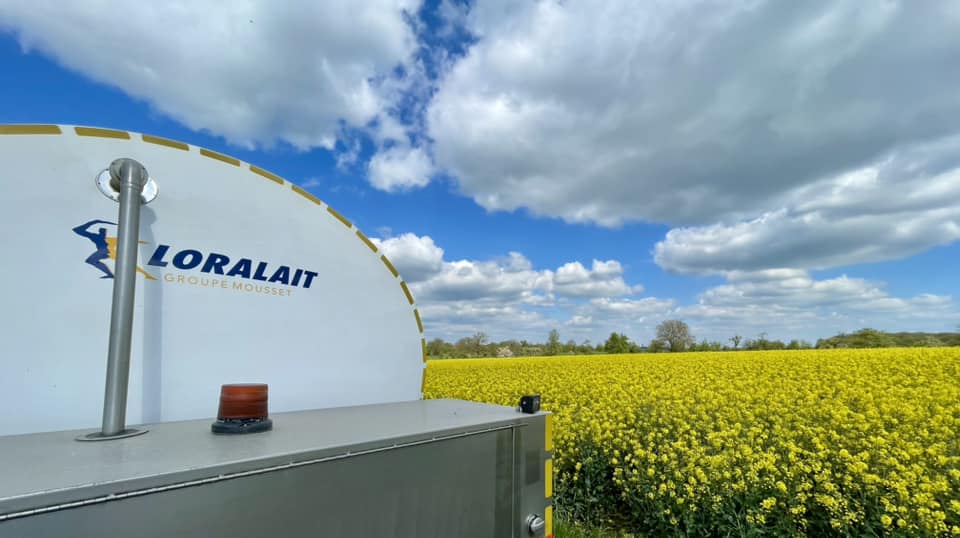 Citerne de lait LORALAIT devant un champ de colza