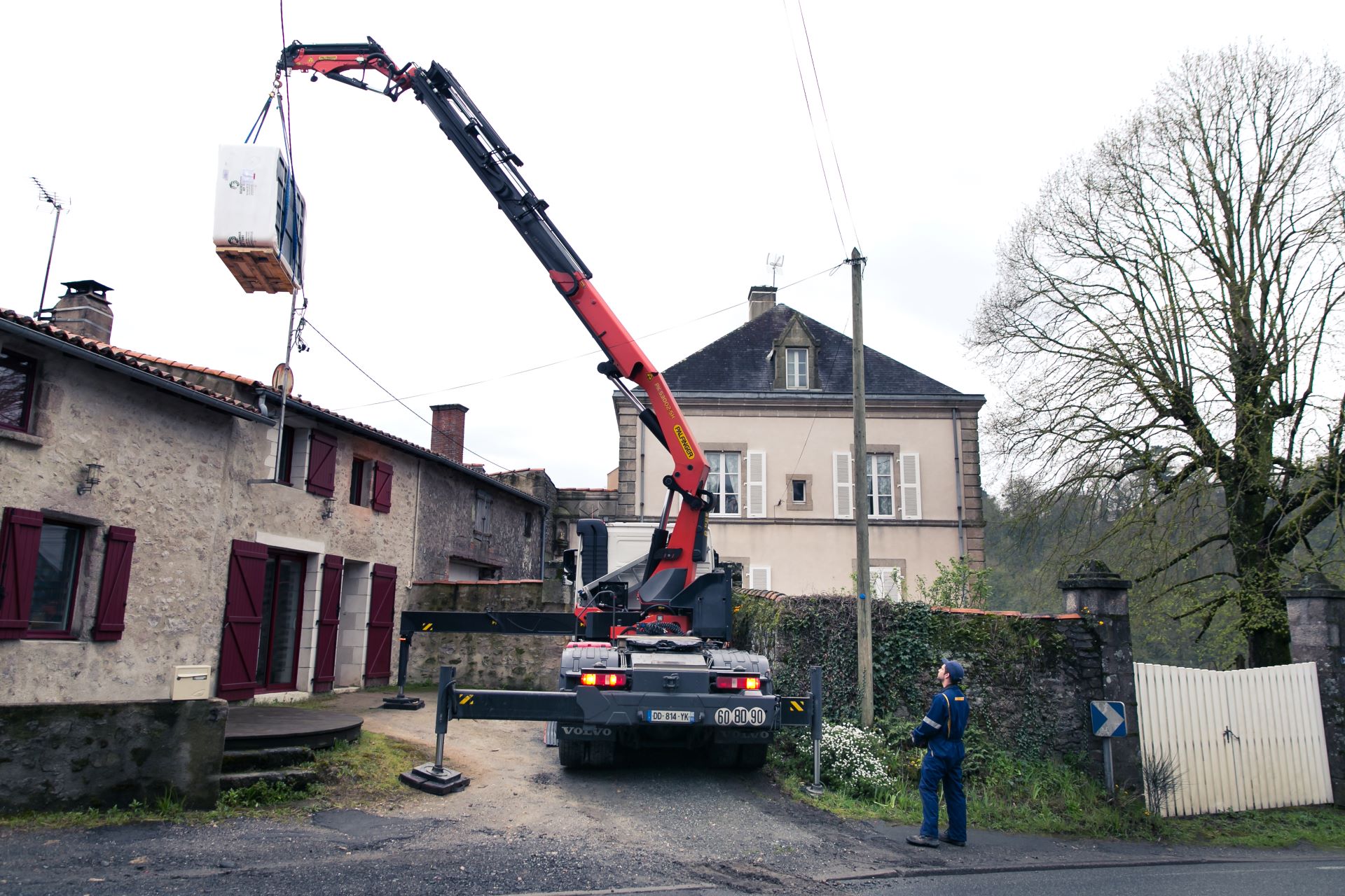 Tracteur avec la grue qui soulève de la marchandise chez un client