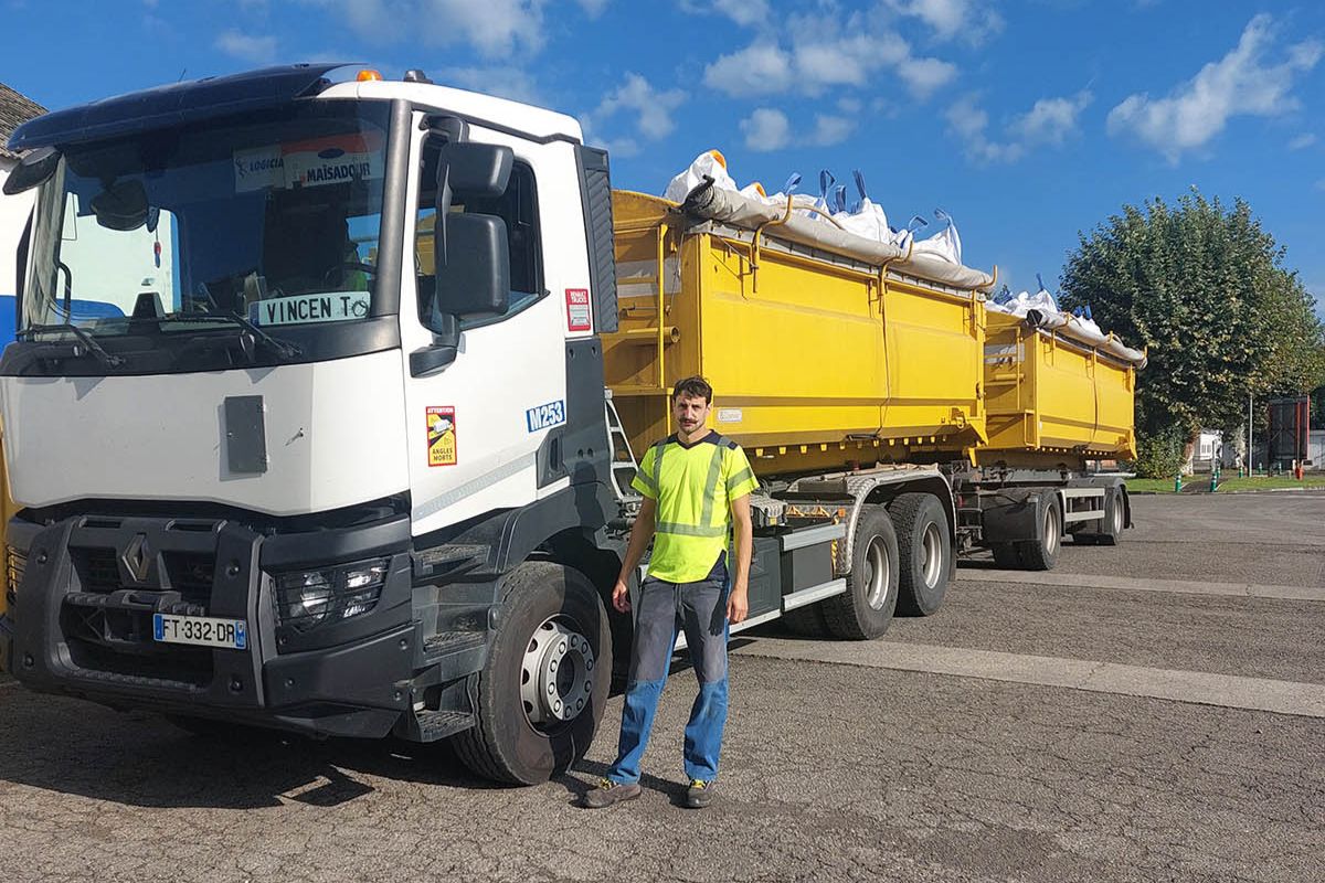 Conducteur devant un camion avec deux bennes de transport d'agro fournitures